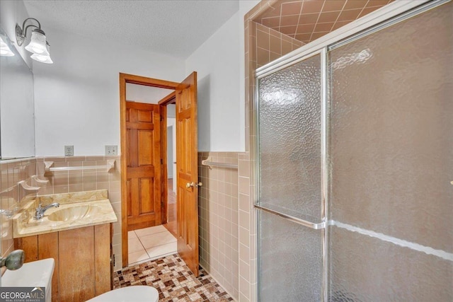 full bathroom featuring a shower stall, tile walls, vanity, tile patterned flooring, and wainscoting