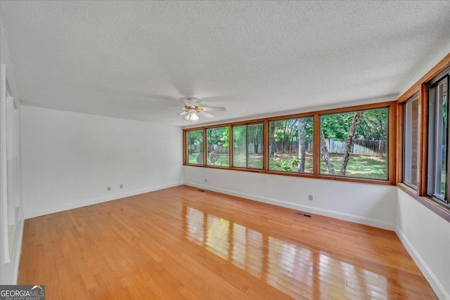 unfurnished room with a textured ceiling, visible vents, a ceiling fan, and light wood finished floors