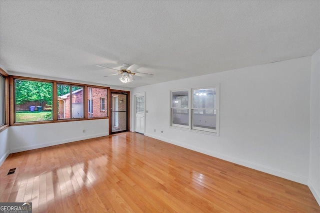 empty room with a textured ceiling, visible vents, ceiling fan, light wood-style floors, and baseboards