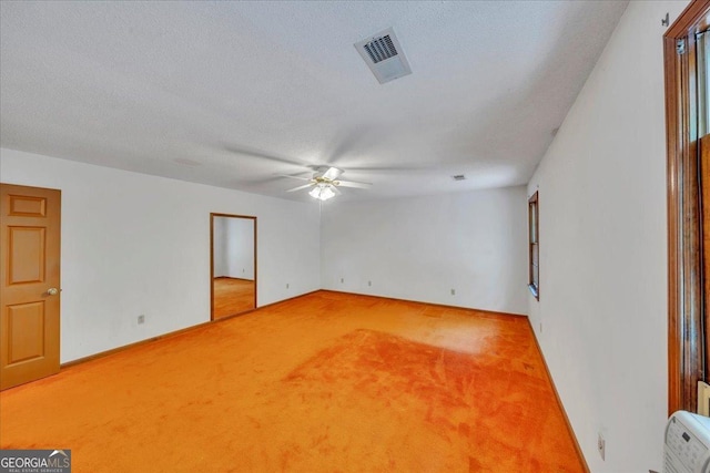 carpeted empty room featuring baseboards, visible vents, ceiling fan, and a textured ceiling