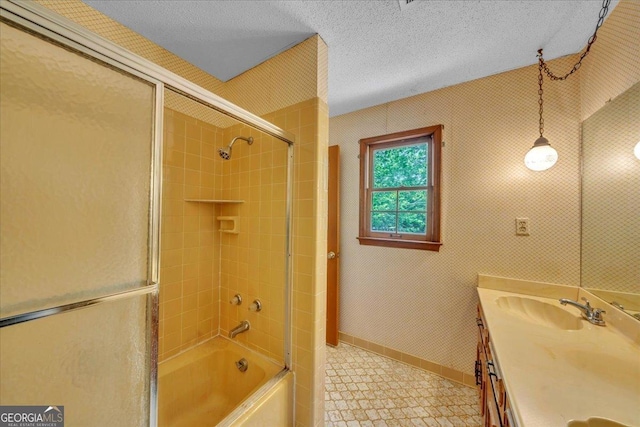 bathroom with a sink, combined bath / shower with glass door, double vanity, baseboards, and a textured ceiling