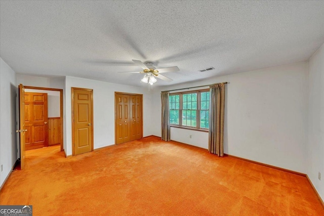 unfurnished bedroom featuring a ceiling fan, visible vents, baseboards, a textured ceiling, and light colored carpet