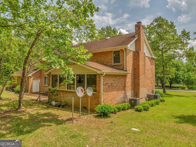 view of side of home featuring a lawn, a chimney, cooling unit, and brick siding