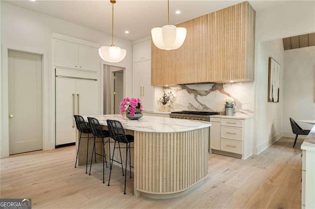 3006 Skyland Dr NE, Brookhaven, GA 30341 - kitchen featuring decorative backsplash, light wood-style flooring, a breakfast bar, paneled fridge, and a kitchen island