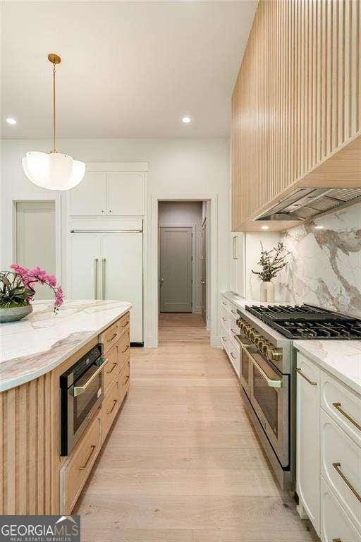 3006 Skyland Dr NE, Brookhaven, GA 30341 - kitchen with light wood-style floors, high quality appliances, white cabinets, backsplash, and premium range hood