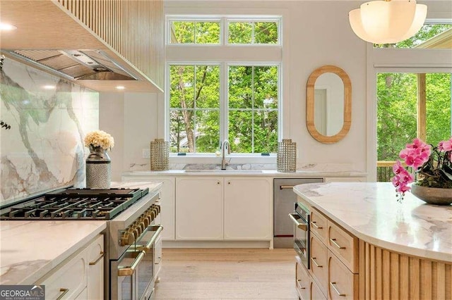 3006 Skyland Dr NE, Brookhaven, GA 30341 - kitchen featuring appliances with stainless steel finishes, white cabinets, light wood finished floors, a sink, and premium range hood