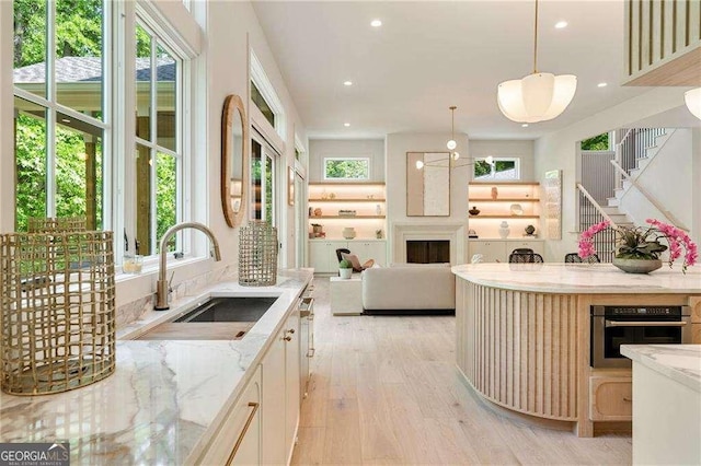 3006 Skyland Dr NE, Brookhaven, GA 30341 - kitchen featuring a healthy amount of sunlight, light wood-style flooring, stainless steel oven, and a sink