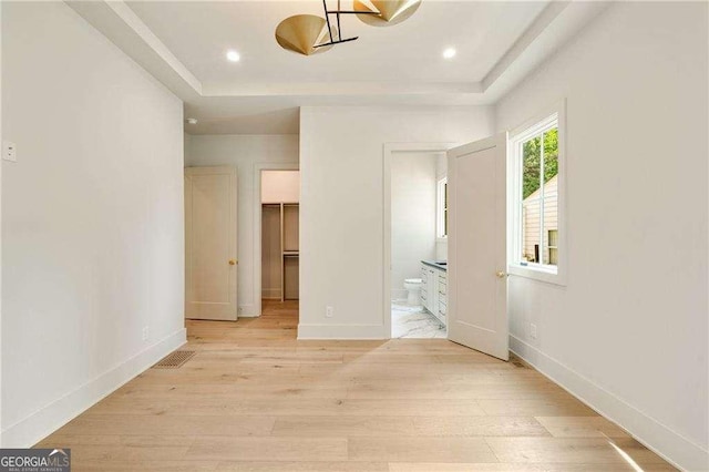 3006 Skyland Dr NE, Brookhaven, GA 30341 - unfurnished bedroom featuring light wood finished floors, a tray ceiling, visible vents, a spacious closet, and ensuite bathroom