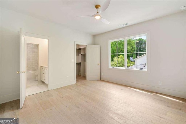 3006 Skyland Dr NE, Brookhaven, GA 30341 - unfurnished bedroom featuring light wood finished floors, connected bathroom, a walk in closet, visible vents, and baseboards