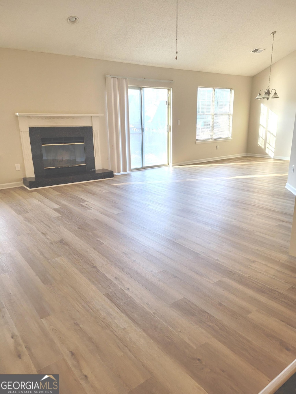 959 Romer Pl, Stone Mountain, GA 30083 - unfurnished living room with wood finished floors, a glass covered fireplace, a chandelier, and baseboards