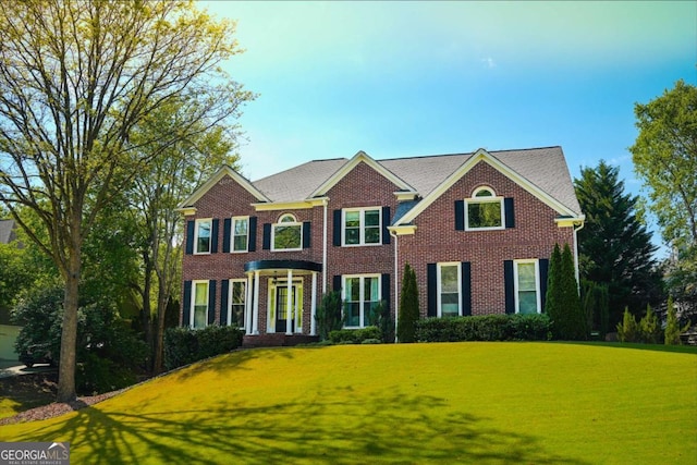 colonial house featuring brick siding and a front lawn