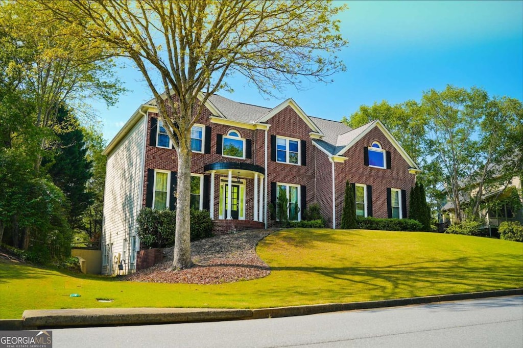 colonial house featuring brick siding and a front lawn