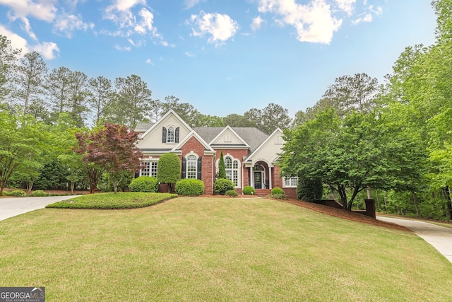 traditional-style home with brick siding, a front lawn, and concrete driveway