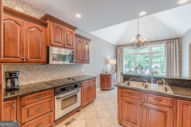 kitchen featuring wallpapered walls, stainless steel appliances, vaulted ceiling, a sink, and light tile patterned flooring