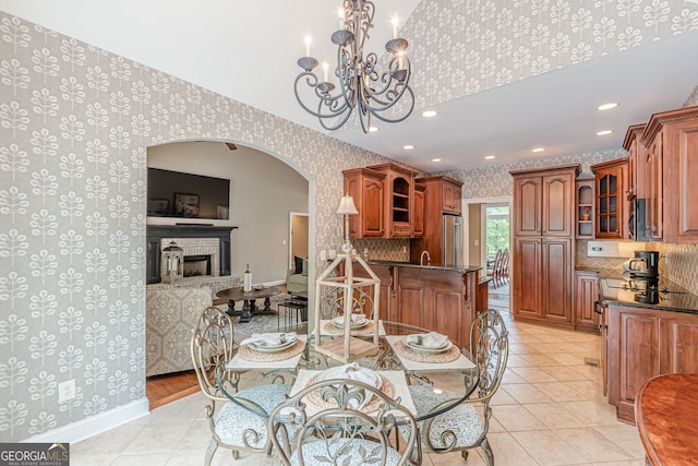 dining room featuring light tile patterned floors, a notable chandelier, baseboards, arched walkways, and wallpapered walls