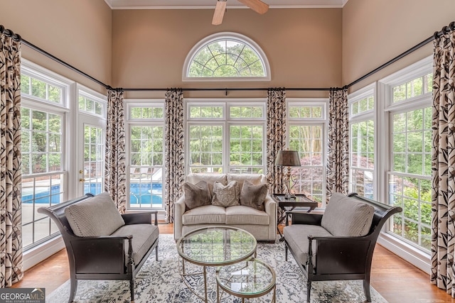sunroom with ornamental molding, a high ceiling, wood finished floors, and french doors