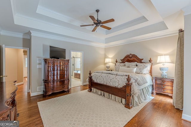 bedroom featuring ceiling fan, wood finished floors, a raised ceiling, and visible vents