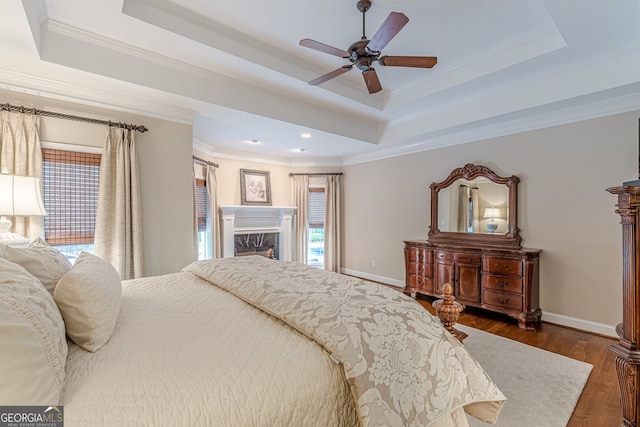 bedroom featuring ornamental molding, dark wood-style floors, baseboards, and a tray ceiling