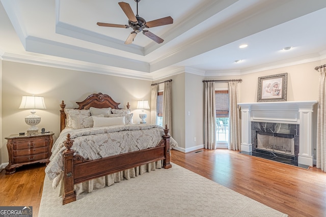 bedroom featuring wood finished floors, access to exterior, ornamental molding, and a high end fireplace