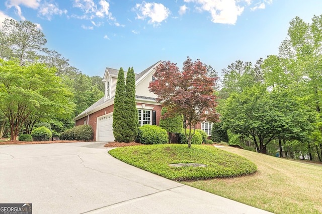 view of side of property featuring concrete driveway, a yard, a garage, and brick siding