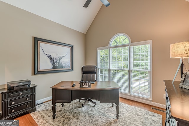 office area featuring baseboards, high vaulted ceiling, ceiling fan, and light wood-style flooring