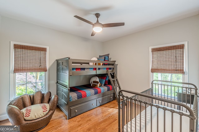 bedroom featuring wood finished floors, a ceiling fan, and multiple windows