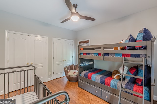 bedroom featuring wood finished floors, ceiling fan, and two closets