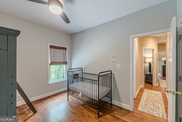 bedroom featuring wood finished floors, ceiling fan, visible vents, and baseboards