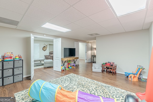 bedroom featuring baseboards, wood finished floors, and a drop ceiling