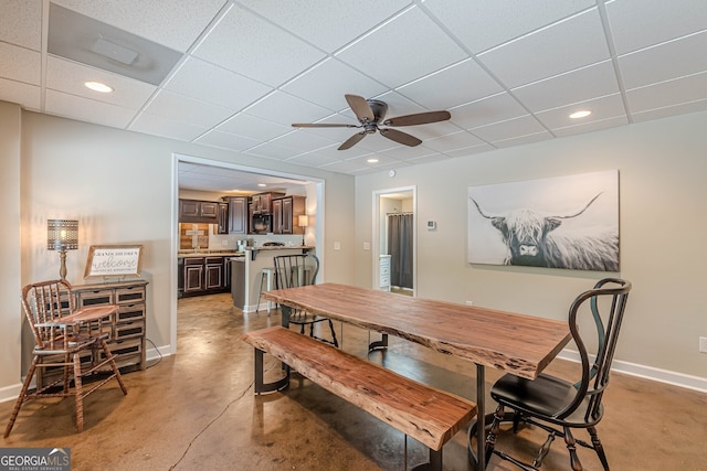 dining space with finished concrete flooring, baseboards, a drop ceiling, recessed lighting, and a ceiling fan