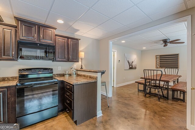 kitchen with a breakfast bar area, dark brown cabinetry, black appliances, a drop ceiling, and a peninsula