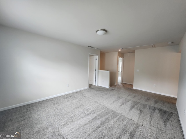 spare room with baseboards, visible vents, attic access, and carpet