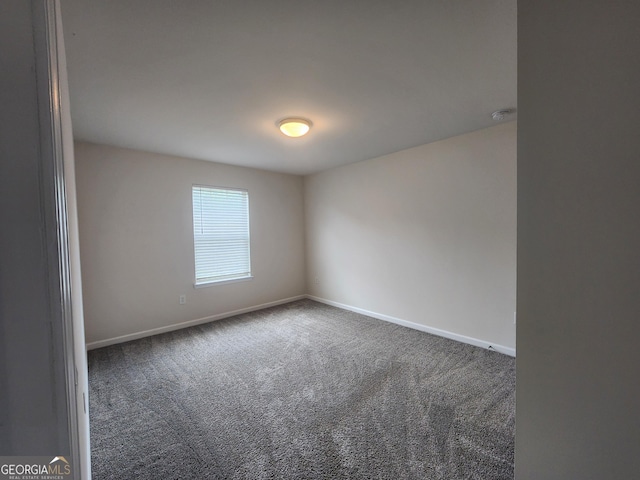 carpeted spare room featuring baseboards