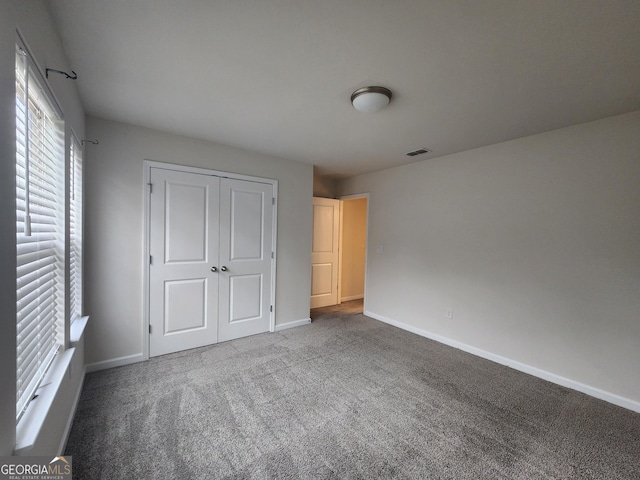 unfurnished bedroom featuring a closet, visible vents, carpet, and baseboards