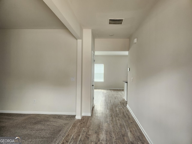 hall with wood finished floors, visible vents, and baseboards