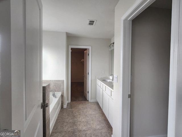 full bath with visible vents, a spacious closet, a garden tub, and vanity
