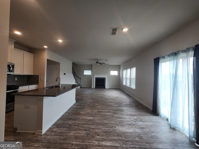 kitchen with recessed lighting, a sink, stainless steel appliances, a fireplace, and dark countertops