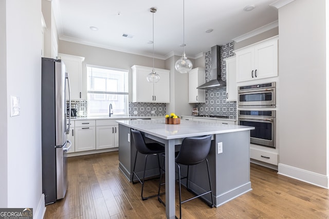 834 S Columbia Dr, Decatur, GA 30030 - kitchen with wall chimney exhaust hood, appliances with stainless steel finishes, a kitchen island, backsplash, and ornamental molding