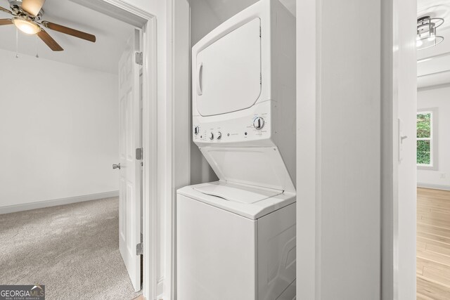 laundry area featuring carpet floors, stacked washer and clothes dryer, a ceiling fan, and baseboards