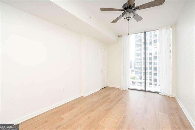 3040 Peachtree Rd NW Unit 815, Atlanta, GA 30305 - unfurnished room featuring healthy amount of natural light, wood finished floors, expansive windows, baseboards, and ceiling fan