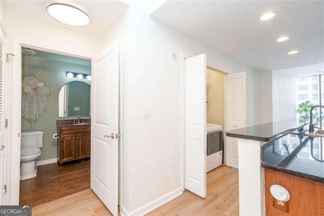 3040 Peachtree Rd NW Unit 815, Atlanta, GA 30305 - kitchen featuring light wood-style flooring, recessed lighting, a sink, baseboards, and washer / dryer
