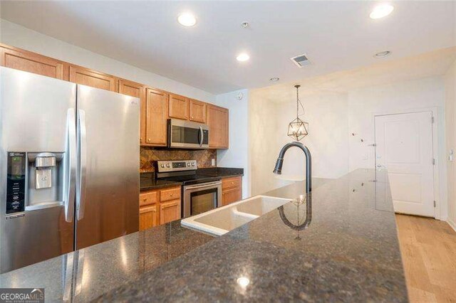 3040 Peachtree Rd NW Unit 815, Atlanta, GA 30305 - kitchen with stainless steel appliances, a sink, decorative backsplash, light wood-type flooring, and decorative light fixtures