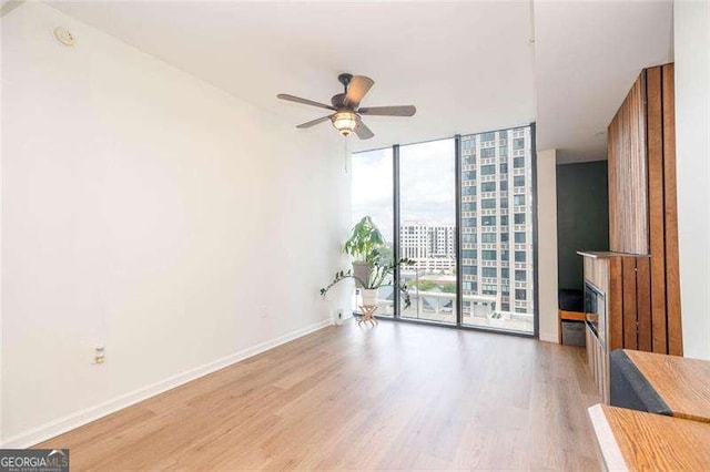 3040 Peachtree Rd NW Unit 815, Atlanta, GA 30305 - spare room with a wall of windows, light wood-style floors, ceiling fan, and baseboards