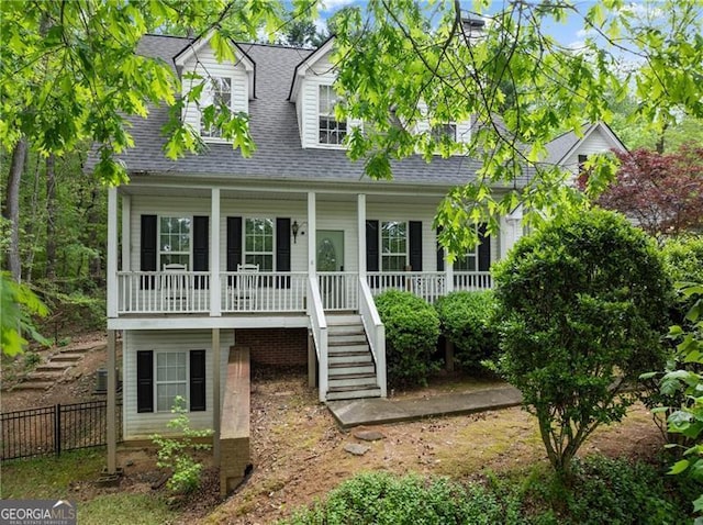 cape cod home with stairs, fence, covered porch, and roof with shingles
