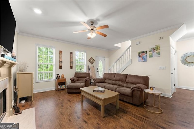 living area featuring crown molding, stairway, ceiling fan, a fireplace, and wood finished floors
