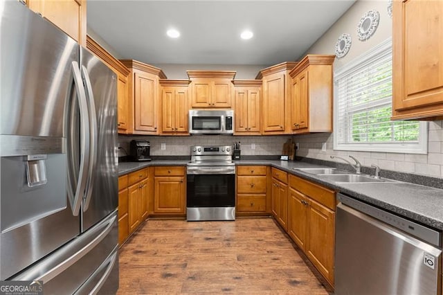 kitchen with wood finished floors, dark countertops, appliances with stainless steel finishes, and a sink