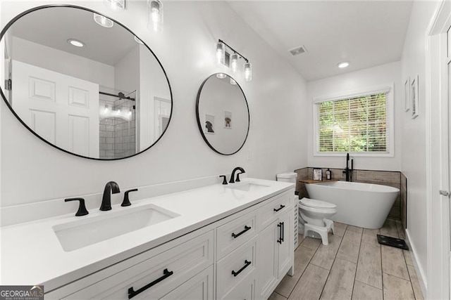 full bath featuring a freestanding tub, recessed lighting, double vanity, and a sink