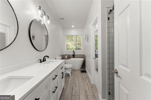 bathroom featuring a freestanding bath, wood finished floors, double vanity, and a sink