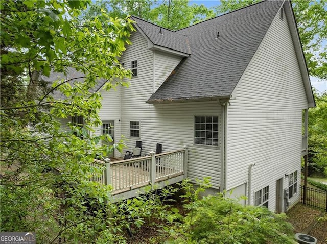 back of property featuring fence, roof with shingles, and a deck
