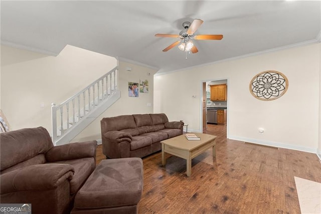 living area featuring wood finished floors, ornamental molding, baseboards, stairway, and a ceiling fan